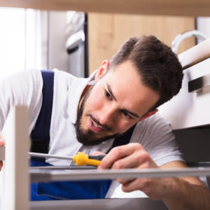 Close-up Of A Young Male Carpenter Installing Drawer With Screwdriver
